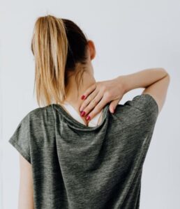 Woman holding her upper back in pain