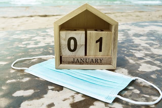 Beach setting, with a block calendar showing January and a disposable mask underneath it