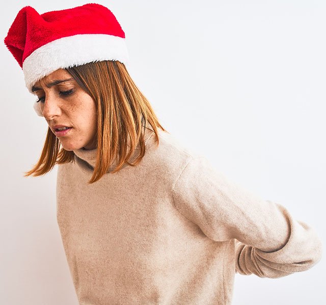 Women wearing a Santa hat holding lower back in pain